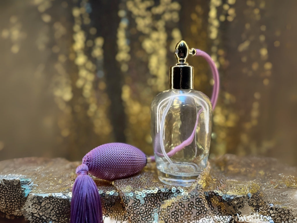 Clear glass perfume bottle with Pink cap and tassel on a glittery surface