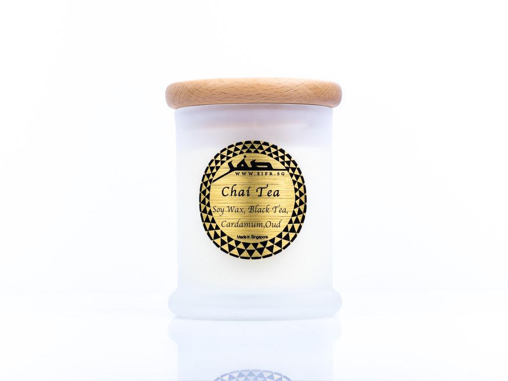 Medium 'Chai Tea' candle in a white container with a wooden lid. The gold label with black text reads 'Chai Tea, Soy Wax, Black Tea, Cardamom, Oud,' and features the Sifr Aromatics logo in black