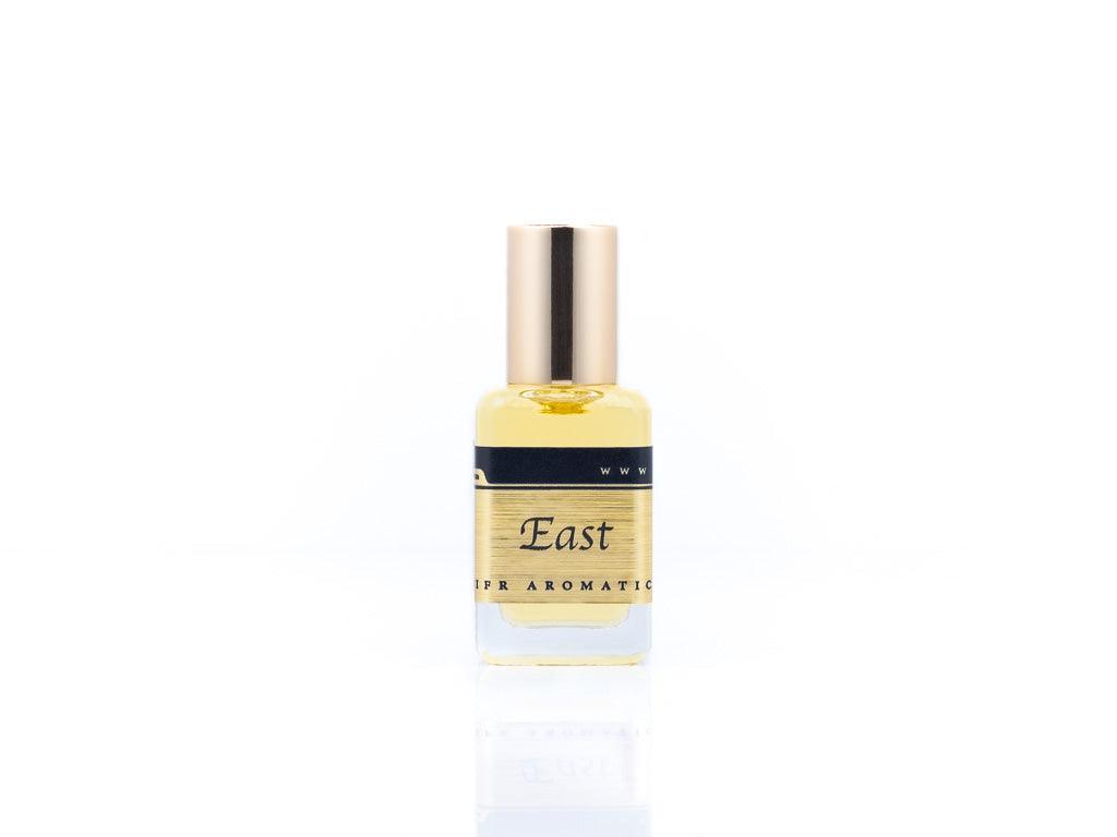 15ml roller ball oil perfume bottle placed elegantly on a white background. The bottle is sleek and cylindrical, with a smooth glass body and a polished metal roller ball at the top. The label on the bottle is designed in gold and black, featuring Sifr Aromatics' logo and the perfume name 'East.' The overall aesthetic is clean and sophisticated, highlighting the high-quality craftsmanship of the product
