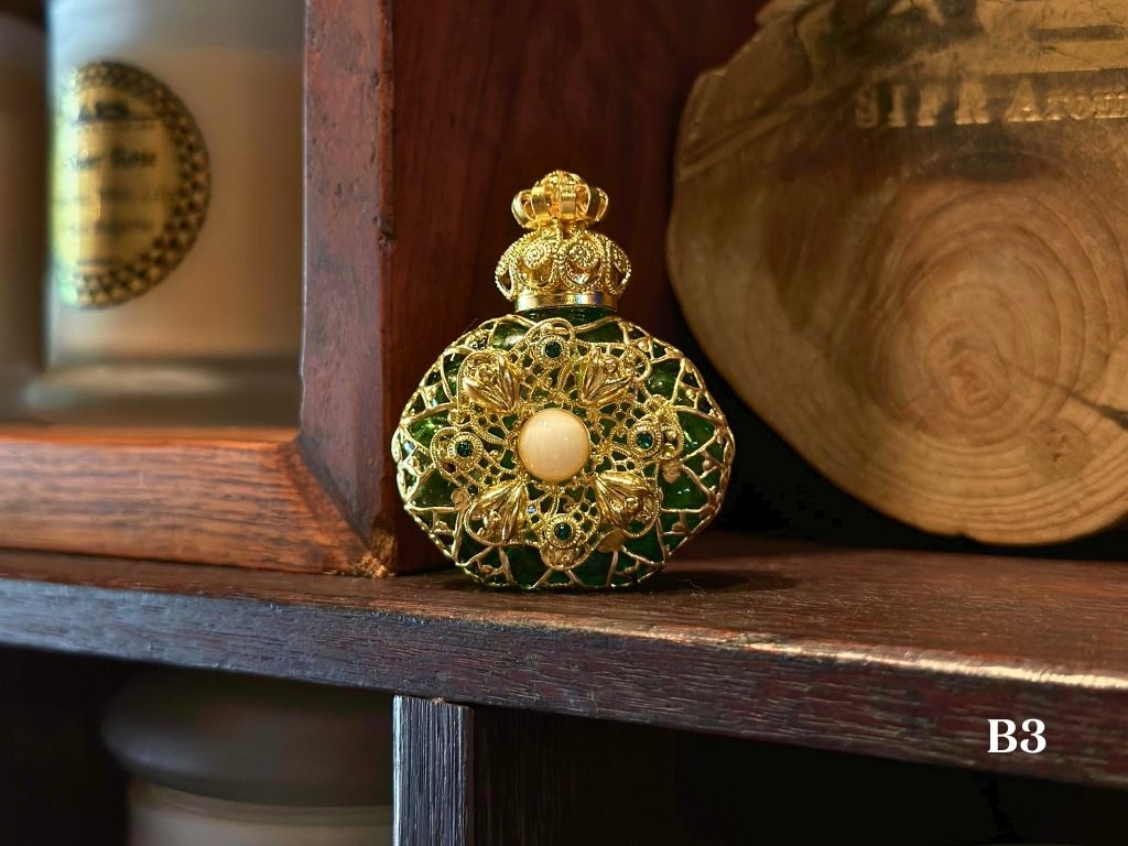 Decorative bottle with gold and green design on a wooden shelf