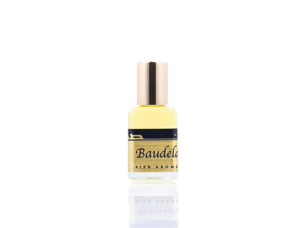 15ml roller ball oil perfume bottle placed elegantly on a white background. The bottle is sleek and cylindrical, with a smooth glass body and a polished metal roller ball at the top. The label on the bottle is designed in gold and black, featuring Sifr Aromatics' logo and the perfume name 'Baudelaire.' The overall aesthetic is clean and sophisticated, highlighting the high-quality craftsmanship of the product