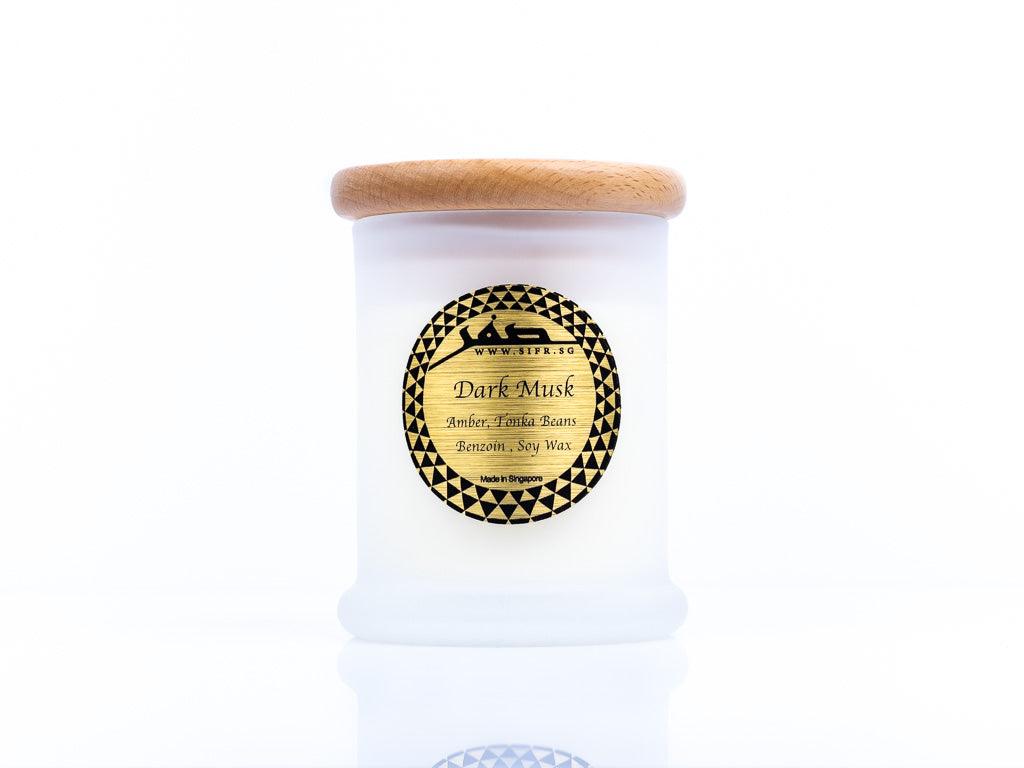 Medium 'Dark Musk' candle in a white container with a wooden lid. The gold label with black text reads 'Dark Musk, Soy Wax, Amber, Tonka Beans, Benzoin,' and features the Sifr Aromatics logo in black