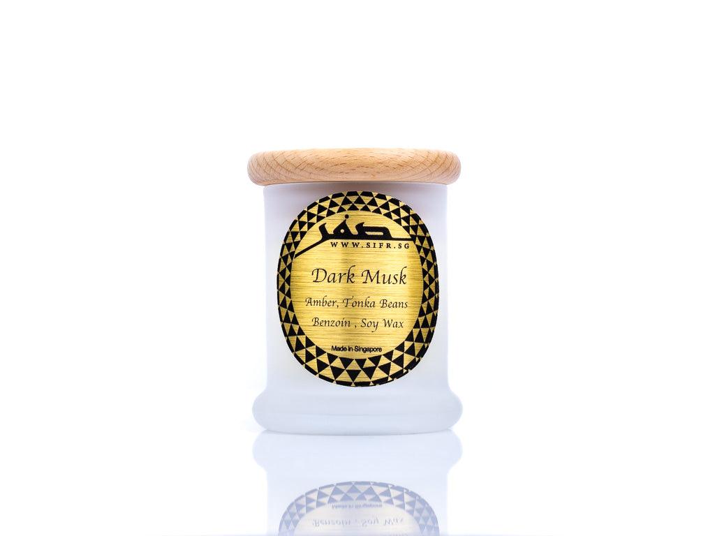 Small 'Dark Musk' candle in a white container with a wooden lid. The gold label with black text reads 'Dark Musk, Soy Wax, Amber, Tonka Beans, Benzoin,' and features the Sifr Aromatics logo in black